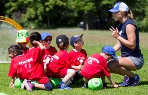 kids playing soccer with coach outside sports activity