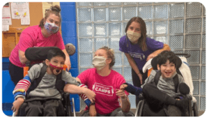 kids in wheelchairs smiling with staff