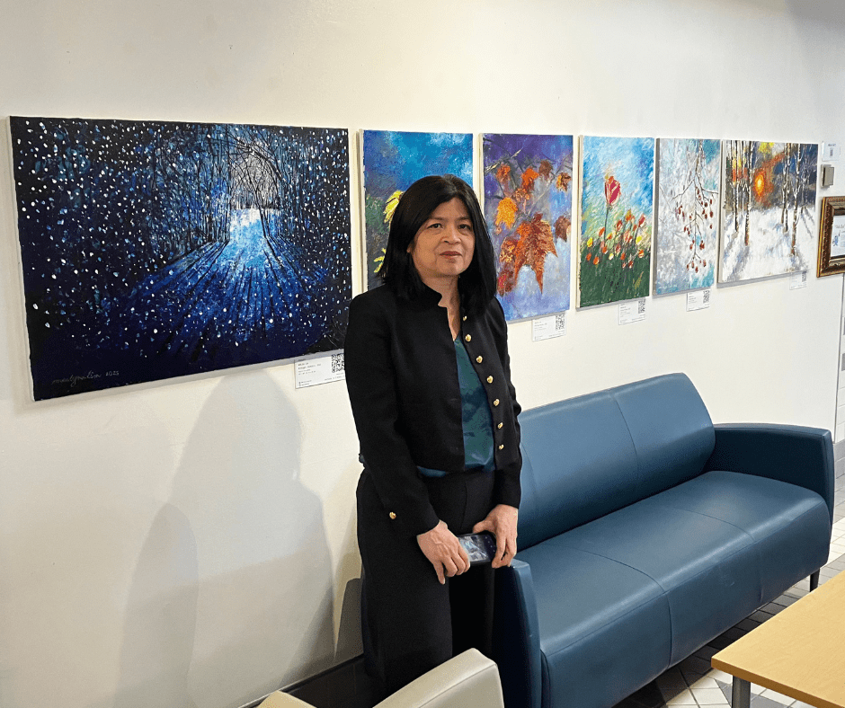 artist standing in front of her paintings